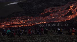 People watch flowing river of magma at Geldingadalir volcano, Iceland 2021