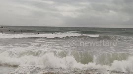 Surfers surfing on Beautiful Waves, on a stormy, windy winter day at Barceloneta beach, Barcelona