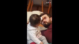 Insistent baby pulls open dad's eyes as he pretends to be asleep