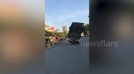 Overloaded truck leans dangerously to one side along road in Cambodia