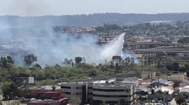 Chopper drops water to douse fire near San Diego freeway