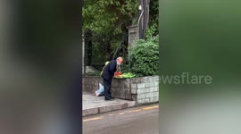 Elderly Chinese vendor uses mouth to spray water over vegetables