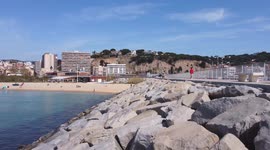 Flying over rocks in Arenys de Mar Port and Beach