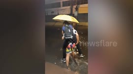 Woman receives piggyback from boyfriend so she can cross flooded road in Philippines