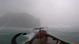 Wooden longtail boat navigates choppy seas during storm in Thailand