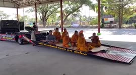 Buddhist monks loaded on truck by conveyor belt, ready for travel to religious festival