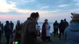Pagans celebrate May Day and Beltane at the Glastonbury Tor as the sun rises above the horizon