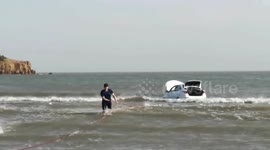 Chinese firefighters drag vehicle to shore after motorist parks on beach as tide rises