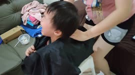 Two-year-old toddler screaming while getting his hair cut by his dad