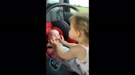 Big sister playing with her baby brother . Laughing together in the car