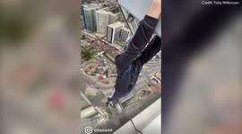 Foolhardy daredevil hung from a London skyscraper with his fingertips