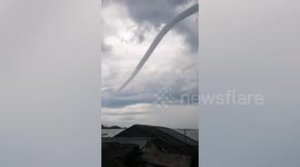 Long thin waterspout tornado looms over beach in the Philippines