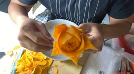 Man sculpting rose with many beautiful petals from pumpkin