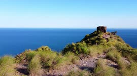 Calblanque coast aerial drone shot of hiking sportsman at the summit of the mountain against spanish seascape.