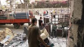 Palestinians collect their belongings from Al-Jawhara tower destroyed during Israeli airstrikes