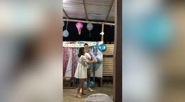 Couple use fire extinguisher with coloured powder for gender reveal party