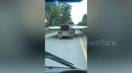 Bungling truck driver carries wide load of metal on the back of vehicle