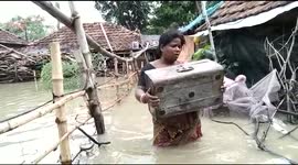 Locals wade through waist-deep water with belongings after Cyclone Yaas floods homes