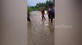Residents help each other carry motorcycles through flood in the Philippines