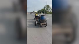 Customised seven-wheeled motorbike with DIY wooden trailer drives along road