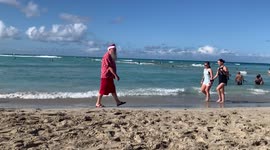 Santa Claus nonchalantly walks down the beach in Honolulu