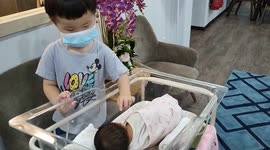 Precious moment of brother cuddling newborn baby sister
