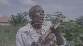 Old African man playing one of african music instruments