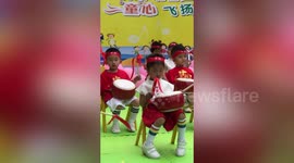 Girl playing drums on stage in China desperately tries to stay awake