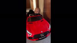 Happy babyboy dancing and “singing” in s red toycar with music