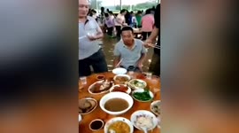 Chinese guests calmly dine outdoors while sitting in knee-deep floodwater