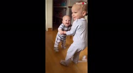 Baby boy delighted as he is helped to walk by his 2-year-old brother