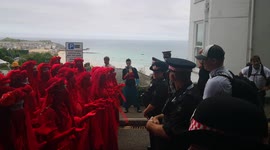 Police cordon off Extinction Rebellion climate protesters dressed in red robes outside G-7 venue