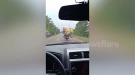 Motorcycle overloaded with snacks rides along highway