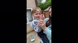 Toddler holding butterfly encouraging it to fly away outdoors