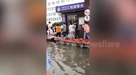 Chinese teachers use tables to build bridge for students to enter flooded school for exams