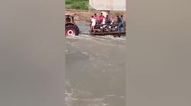Motorcyclists ride on back of truck to cross swollen river