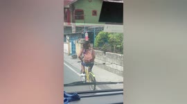 Talented cyclist balances drinking bottle on head while riding along road