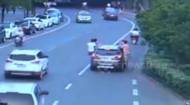 Hitchhikers hang off a car in China