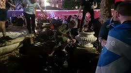 Scottish football fans slip in mud around fountain in London's Leicester Square