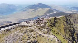 Amazing aerial footage of Snowdonia in Wales. Bank Holiday Summer 2021. Queue on busy Snowdon and scrambling in the UK. Hiking. Snowdon. Blue sky. Mountain.