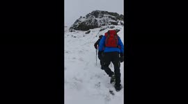 A line of men climbing up a mountain (Ben Ledi) covered in snow. Scotland, Feb 2018.