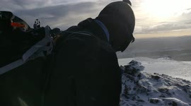 Hikers at the top of a snow-capped mountain in Scotland walking about and talking during a storm. Feb 2018