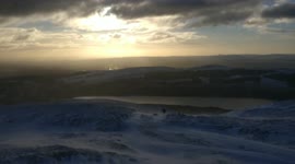 Man walking up the side of a mountain in the snow in Scotland