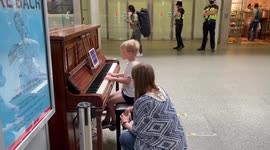 Young boy plays piano at St Pancras International while  waiting
