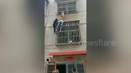 Woman holds up toddler dangling from second-floor window's railings in China