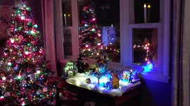 Christmas Tree Decorations with Holiday Village Multicolored Twinkling Lights Night Window Reflection