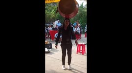 Vietnamese woman juggling a giant drum with her head