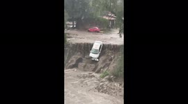 Men pull out a taxi car that was washed off a cliff by a stream of water in Atizapán, Mexico