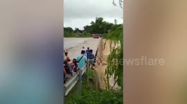 Terrifying moment residents cross bridge submerged in muddy floodwater
