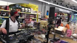 Mobile DJ in England shirt spins tunes as he wanders the aisles of a supermarket in Wembley